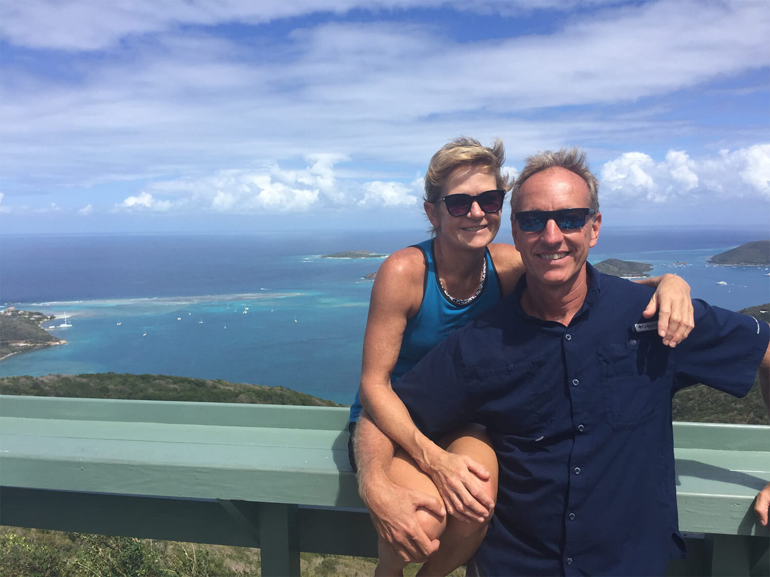 Collin and Corrine, owners of &Beyond Yacht Charters, standing in front of a view of a bay