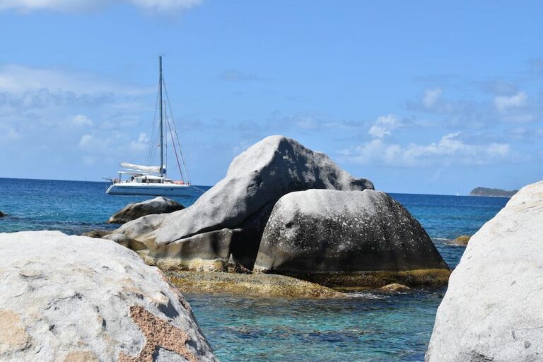 A boulder formation with a yacht anchored in the background