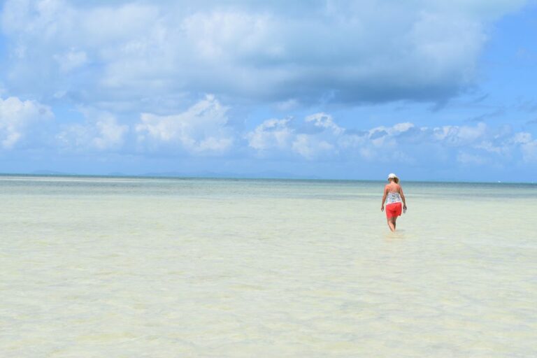 A woman walking through shallow water on a beach in the Virgin Islands