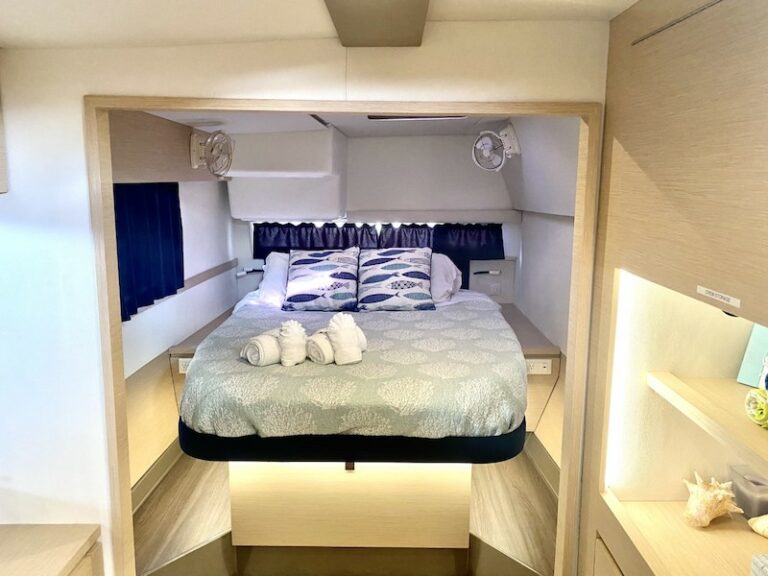 Cabin area with a bed and a stack of towels aboard the Eddies in Time catamaran yacht